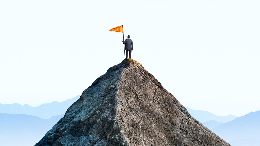 A man holding a flag at on a mountain top.